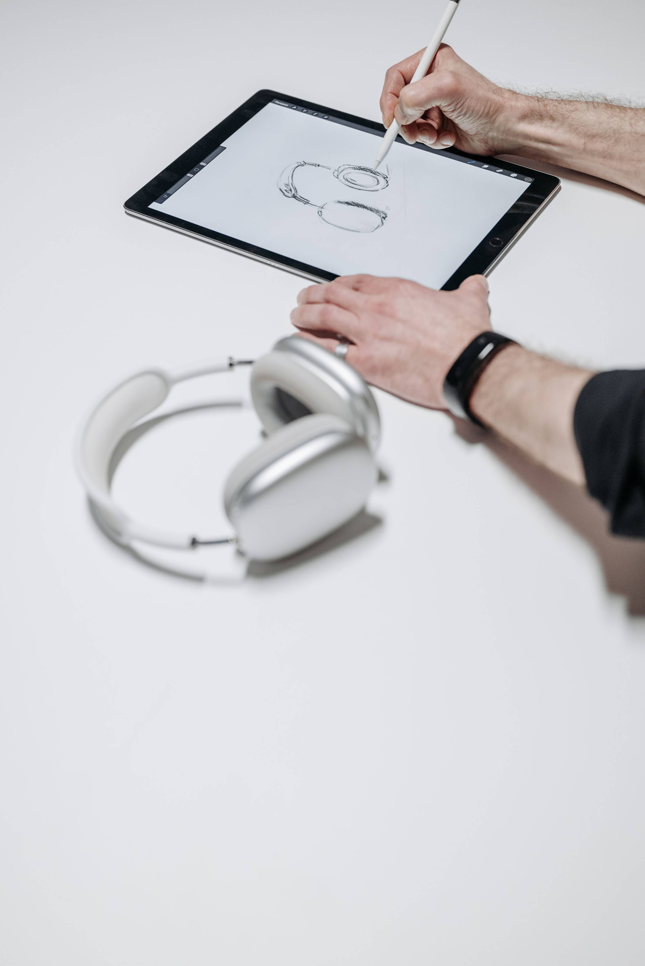 Overhead view of planning materials and cables, hands sketching on tablet